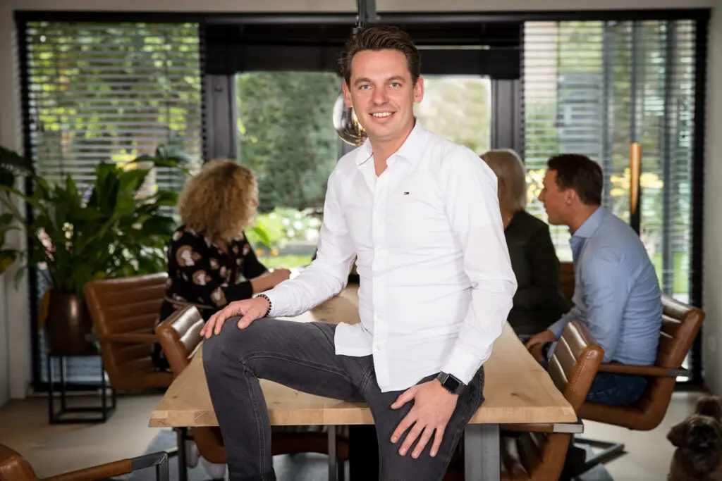 Reinier Veenendaal van Fundament Makelaars op kantoor met collega's op de achtergrond